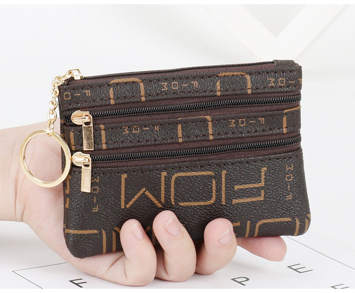 Women's Coin Purse Short and I in black leather with multiple zippered compartments and a keyring attached.